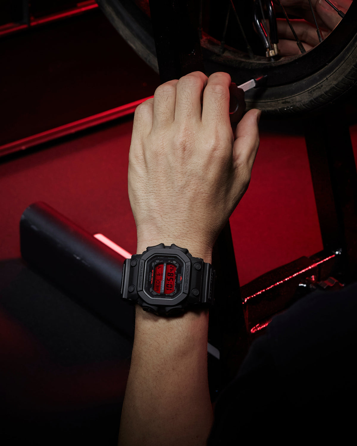 Person adjusting a car tire with a watch on their wrist, set against a red vehicle interior.