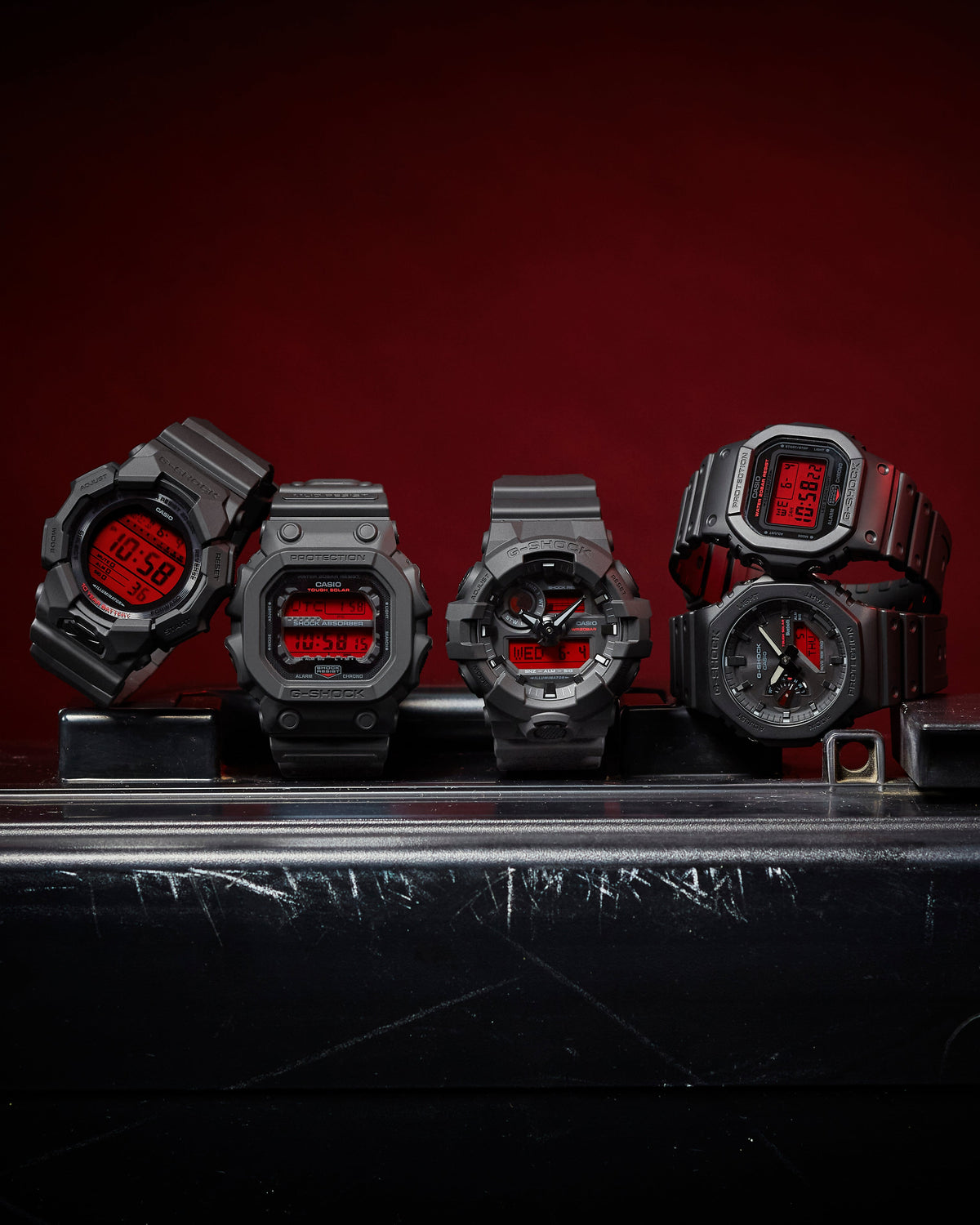 Five black resin watches with red accents on a dark background