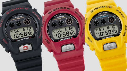 Three Casio G-Shock digital watches in black, red, and yellow with resin bands and illuminated LCD displays.