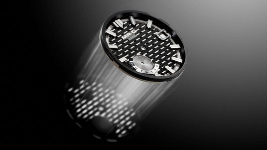 Casio MR-G watch dial with a black grid pattern, silver indices, and a day-of-the-week subdial on a dark background.