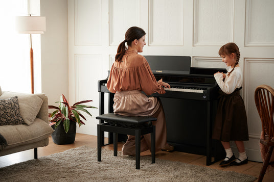 Woman playing a black Casio Celviano AP-550 digital piano while a young girl watches in a bright, modern living room.