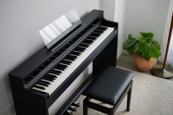 Sleek black Casio Celviano AP-S450 digital piano with a matching bench in a modern, minimalist living room setting.