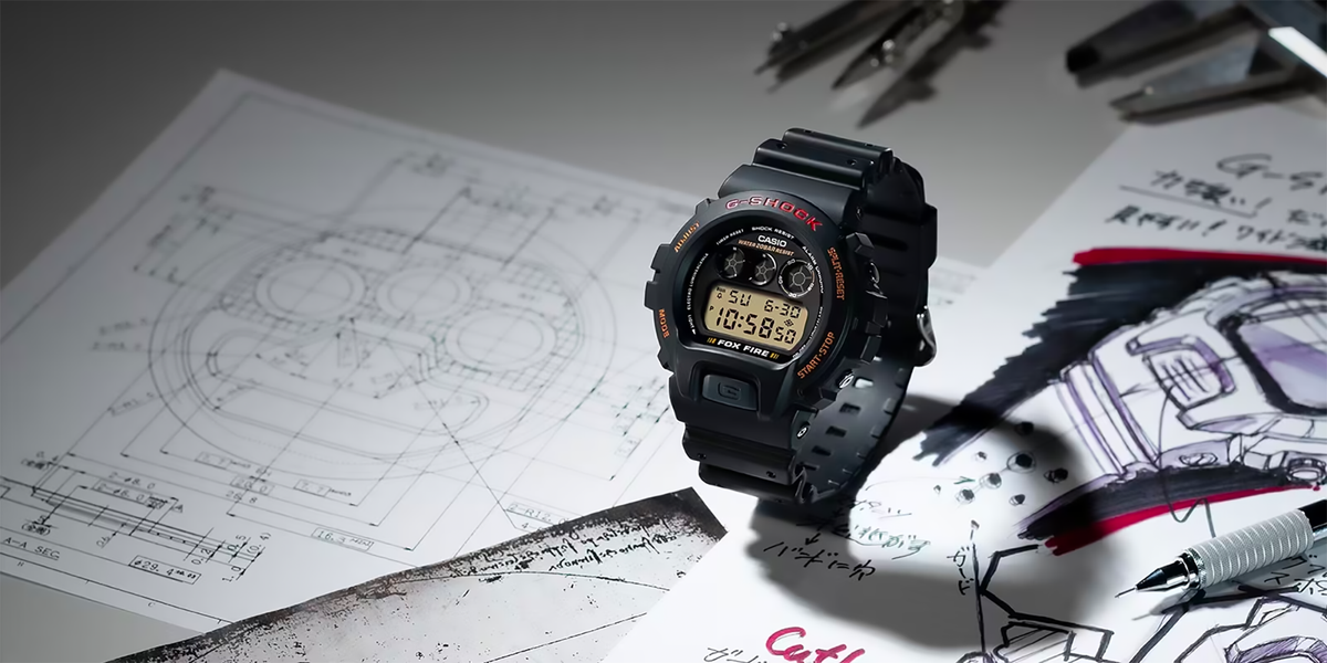 Black Casio G-Shock 6900 series watch on a desk with technical design sketches and drafting tools.