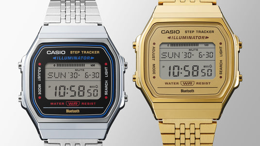 Silver and gold Casio ABL-100WE digital watches with step trackers and Bluetooth connectivity on a grey background.