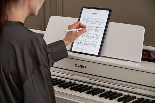 Person using a tablet on a Casio AP-300BN digital piano 