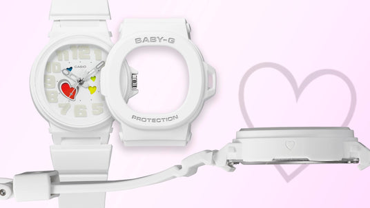 White Baby-G watch with a heart-accented dial, detachable bezel, and side profile view on a soft pink background.