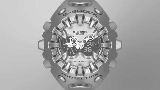 Metallic silver G-Shock watch with a complex, industrial layered dial design and digital display against a gray background.