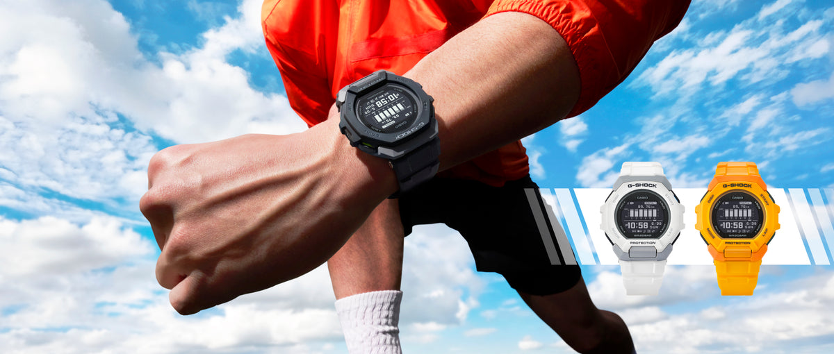 Runner wearing a black G-SHOCK GBD-300 watch with white and orange models displayed against a blue sky.