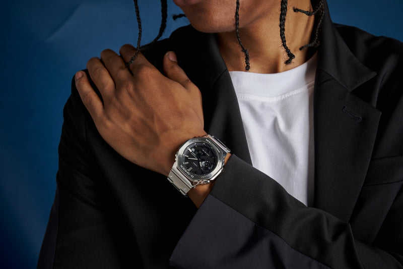 Person wearing a silver stainless steel G-Shock watch with an octagonal bezel and black analog-digital dial.