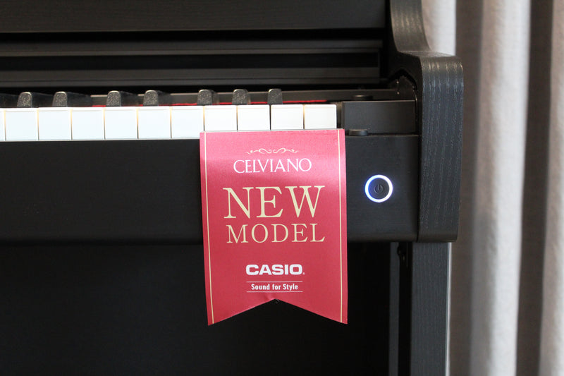 Black Casio Celviano digital piano with a red New Model promotional tag hanging over the white and black keys.