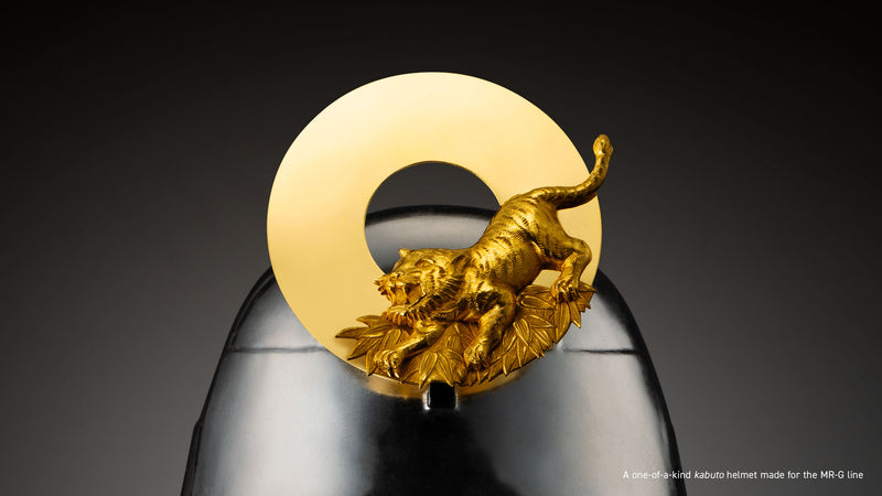 Ornate gold tiger sculpture mounted on a polished dark metal kabuto helmet.