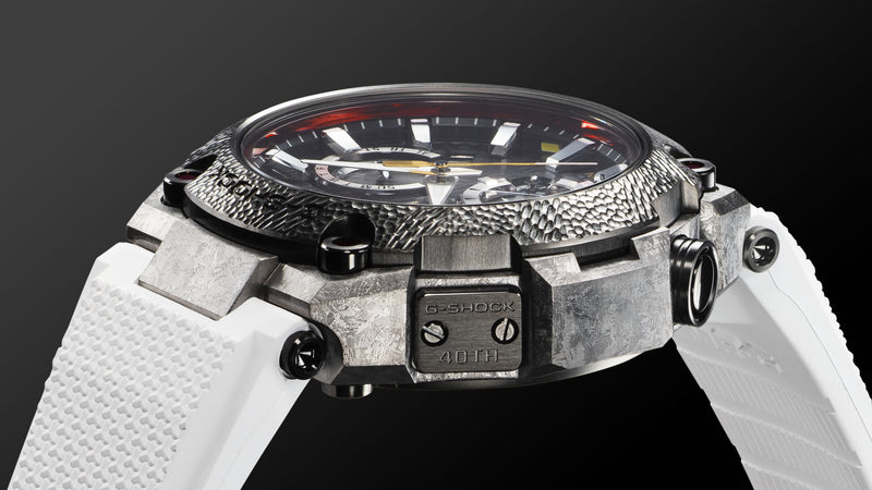 G-Shock MRG-B2000SG watch with a hammered metal bezel, textured grey case, and white rubber strap on a black background.