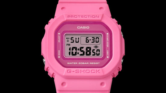 Bright pink Casio G-Shock digital watch with a square face and resin strap against a black background.