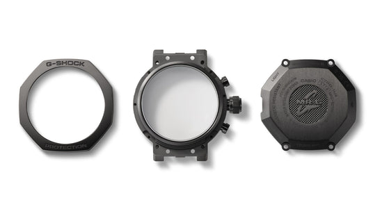 Disassembled black titanium G-Shock MR-G watch components including the octagonal bezel, main case, and engraved case back.