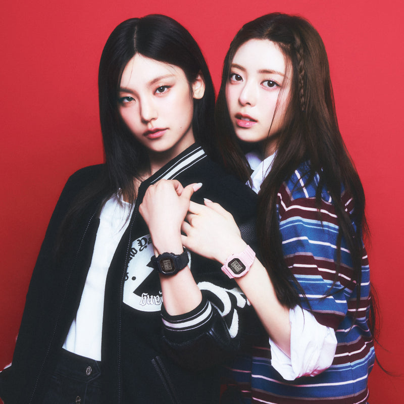 ITZY members wearing black and pink Casio G-Shock watches against a vibrant red background.