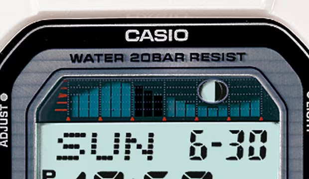 Close-up of a Casio digital watch face showing the date, moon phase indicator, and a tide graph on a light blue display.