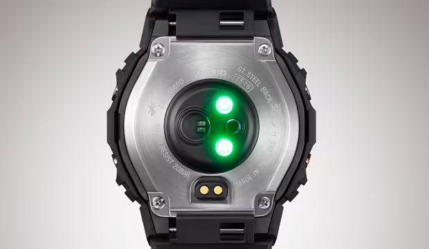 Back view of a black smartwatch with a stainless steel case featuring glowing green heart rate sensors.